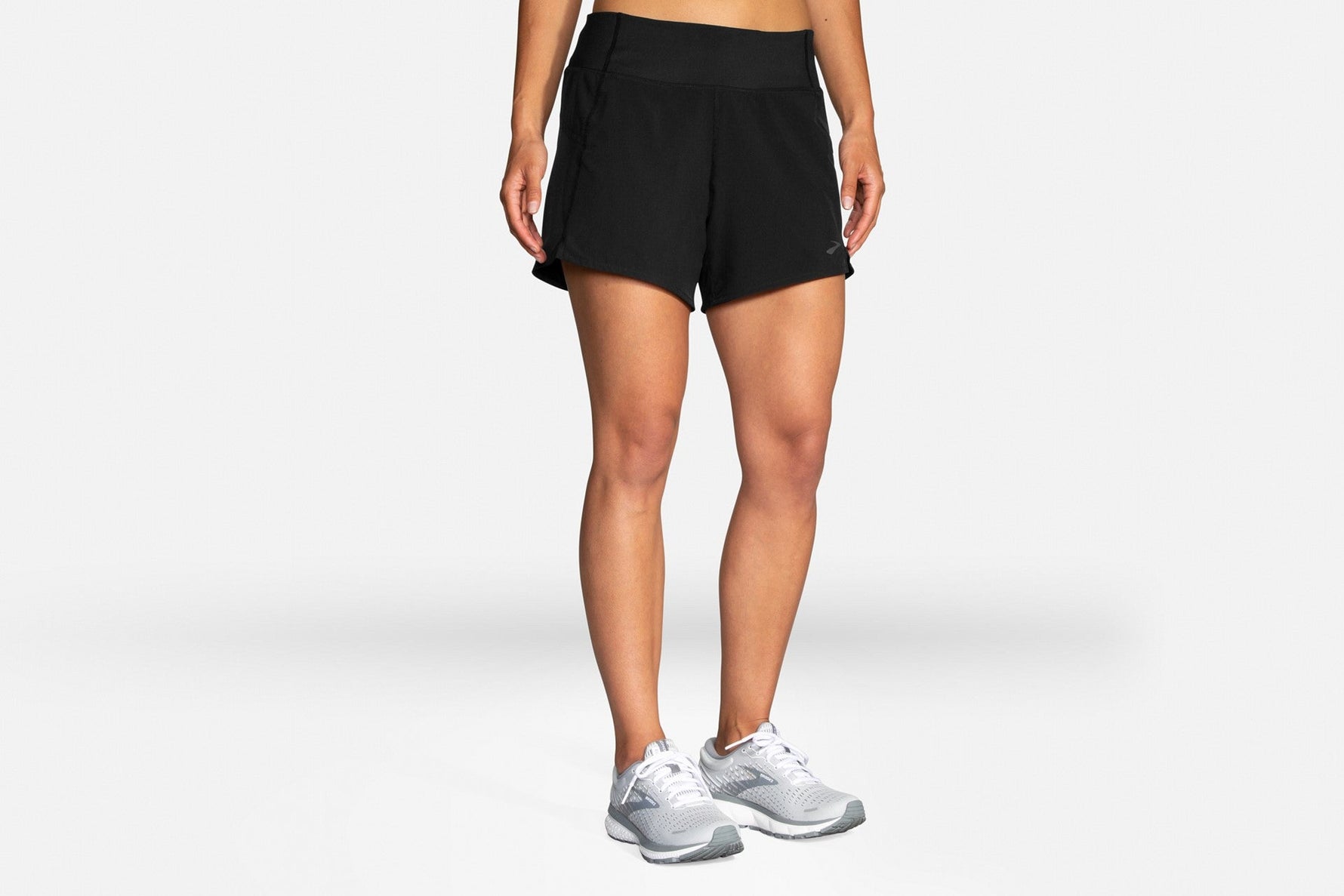 Woman wearing black Brooks Chaser 5-inch running shorts with white sneakers
