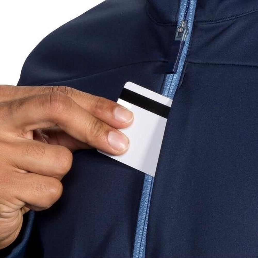Person pulling white card from interior pocket of navy blue Brooks running jacket