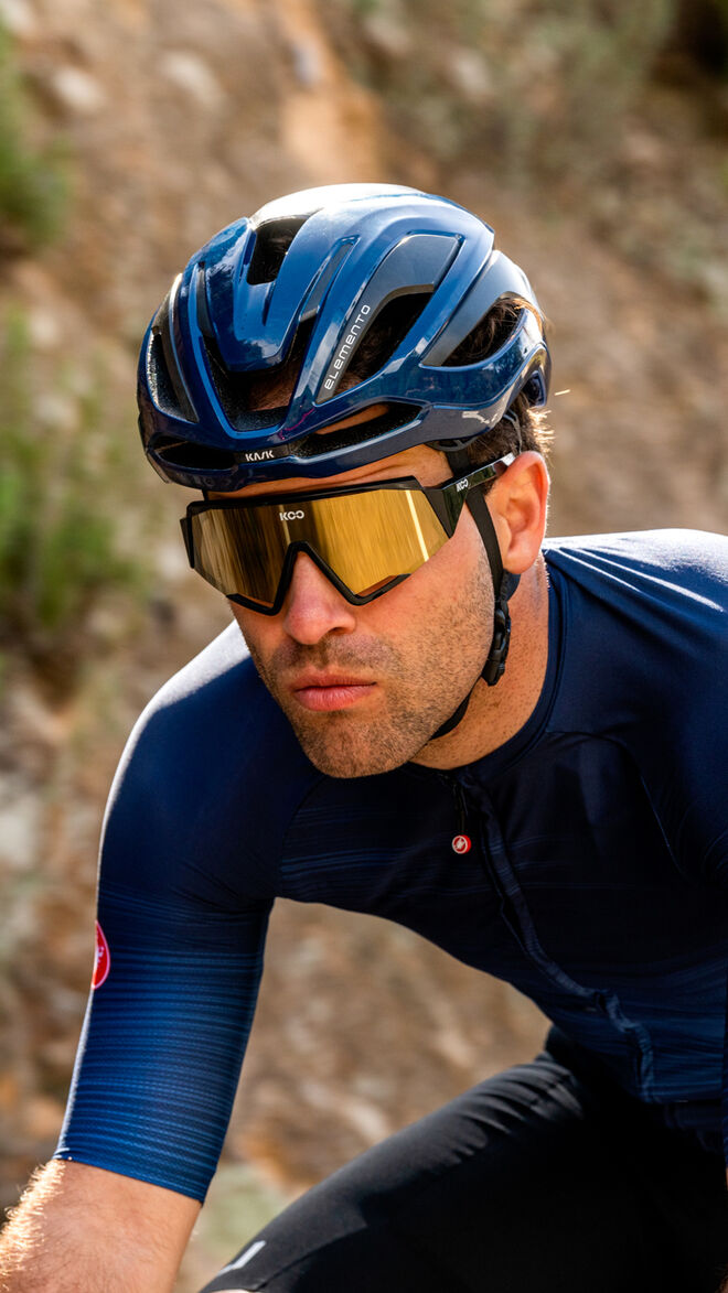 Cyclist wearing blue Kask Protone Icon helmet with gold-tinted sunglasses