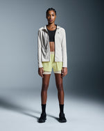 Woman wearing On 3 inch Performance 2/1 Shorts in limelight green with sand waistband
