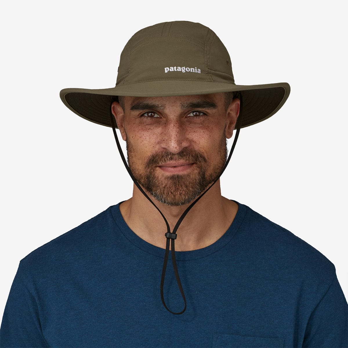 Man wearing Patagonia Quandary Brimmer hat in basin green with chin strap