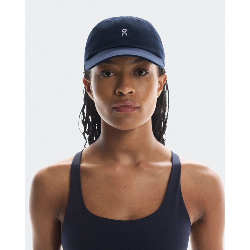 Woman wearing navy blue On lightweight cap with white logo in studio setting