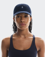 Woman wearing On Lightweight Unisex Cap in navy with matching navy sports top