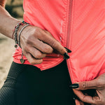 Woman wearing bright coral pink GOBIK cycling vest with zipper detail