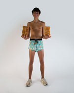 Man wearing turquoise ChicknLegs split shorts with silly goose pattern in studio
