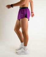 Man wearing purple athletic shorts with black waistband in studio setting
