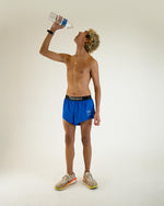 Athletic man wearing Chicknlegs sky blue split running shorts while drinking water