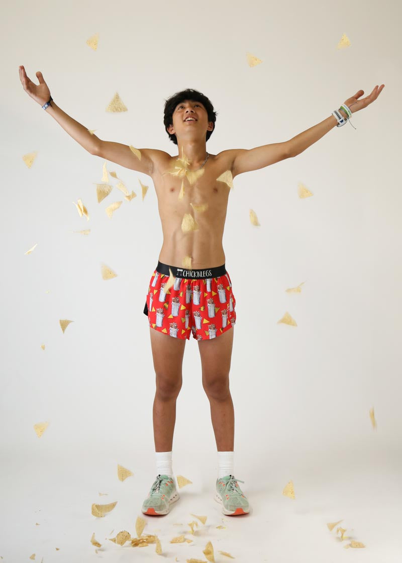 Man wearing red Chicknlegs burrito pattern shorts with arms raised celebrating