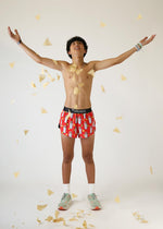 Young man wearing red Chicknlegs burrito print shorts with arms raised in celebration