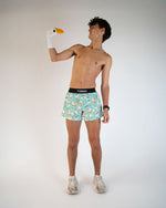 Man wearing ChicknLegs turquoise food-patterned half split shorts with duck sock puppet