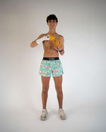 Man wearing ChicknLegs turquoise breakfast-patterned shorts holding toy goose and waffle