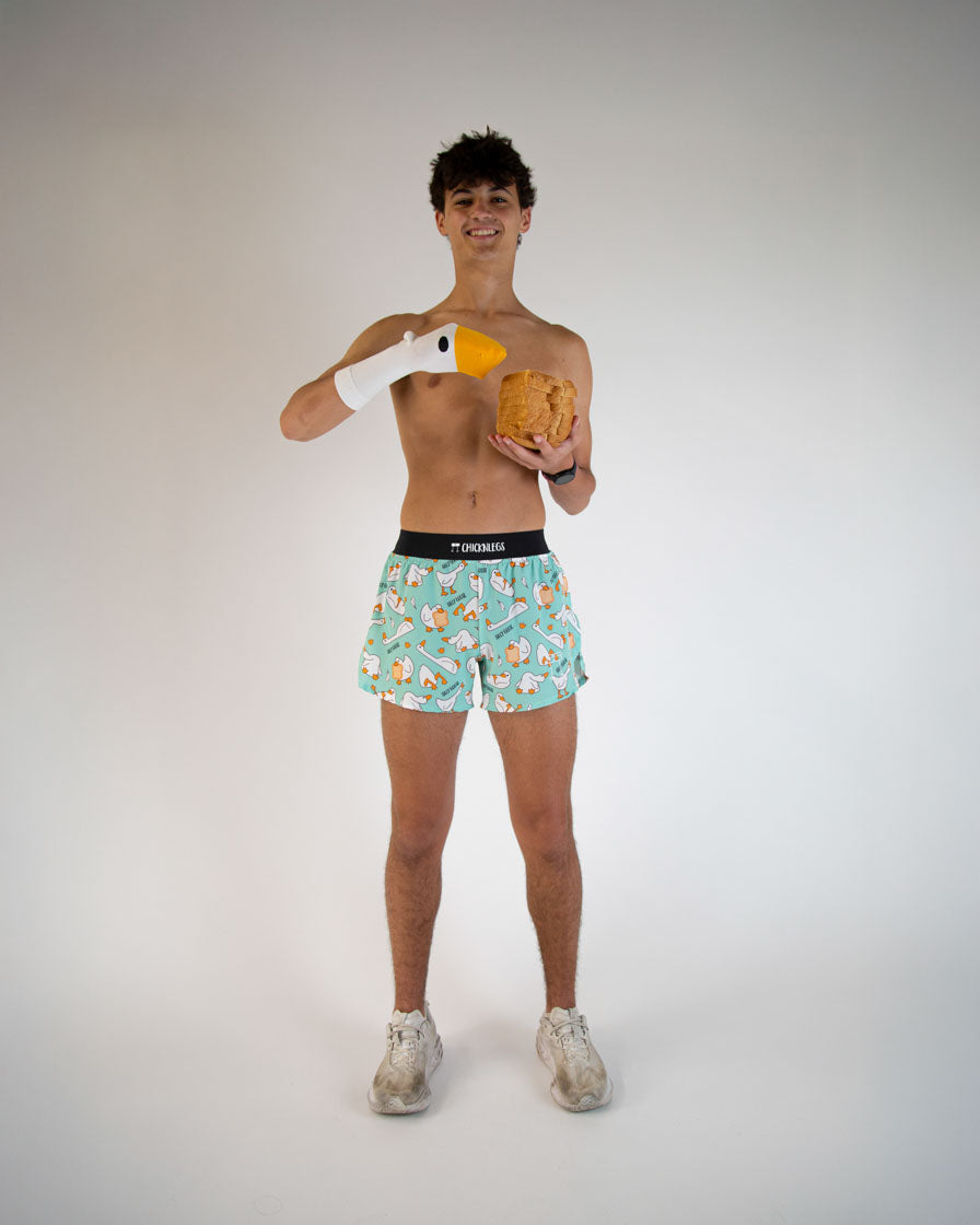 Man wearing ChicknLegs turquoise breakfast-patterned shorts holding toy goose and waffle