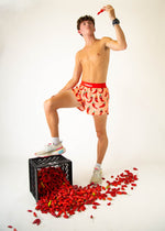 Man wearing ChicknLegs red chili pepper pattern shorts in studio photo