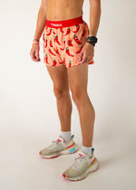 ChicknLegs men's running shorts with red chili pepper pattern on peach background