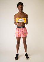 Man wearing pink banana print running shorts holding ChicknLegs brand packaging