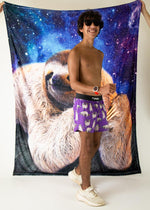 Man wearing purple ChicknLegs boxer shorts with sloth pattern against galaxy backdrop