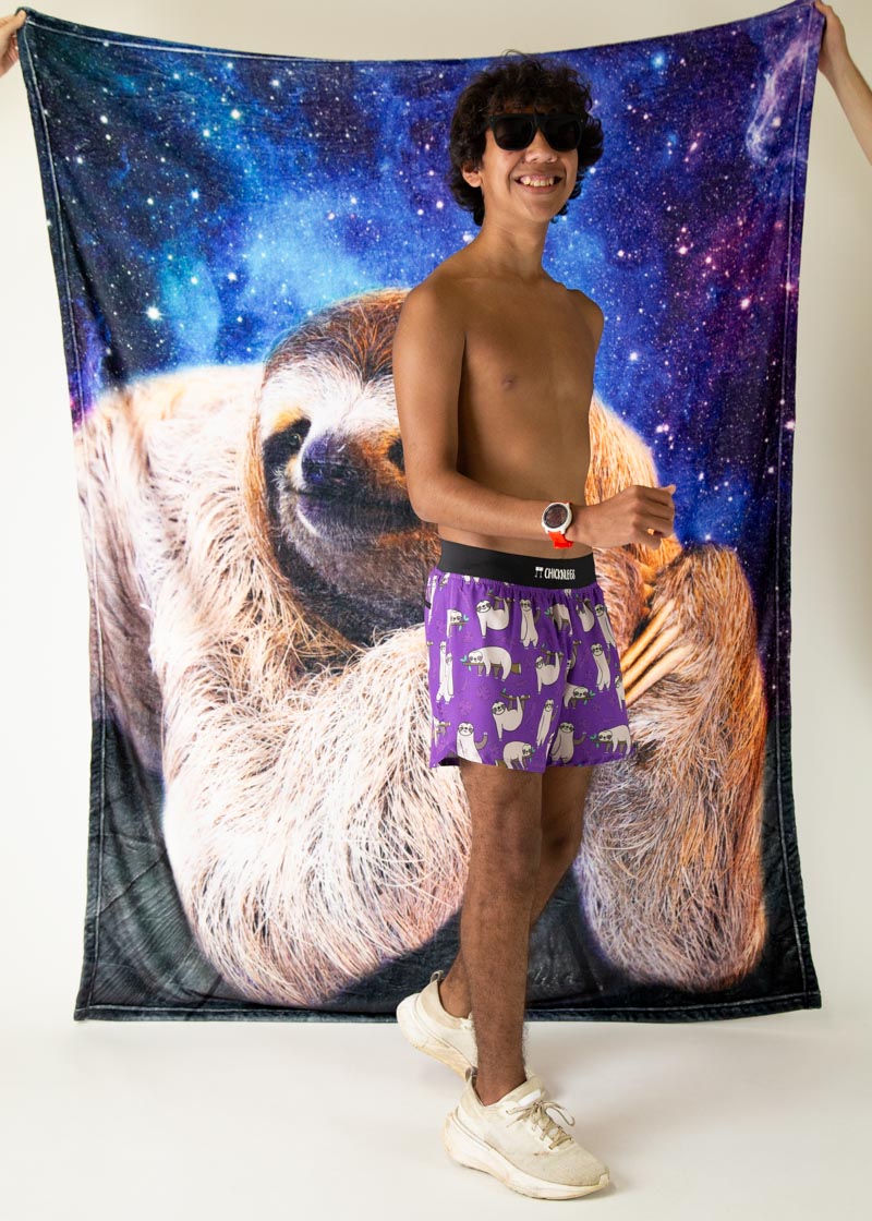 Man wearing purple ChicknLegs sloth pattern shorts against space-themed backdrop