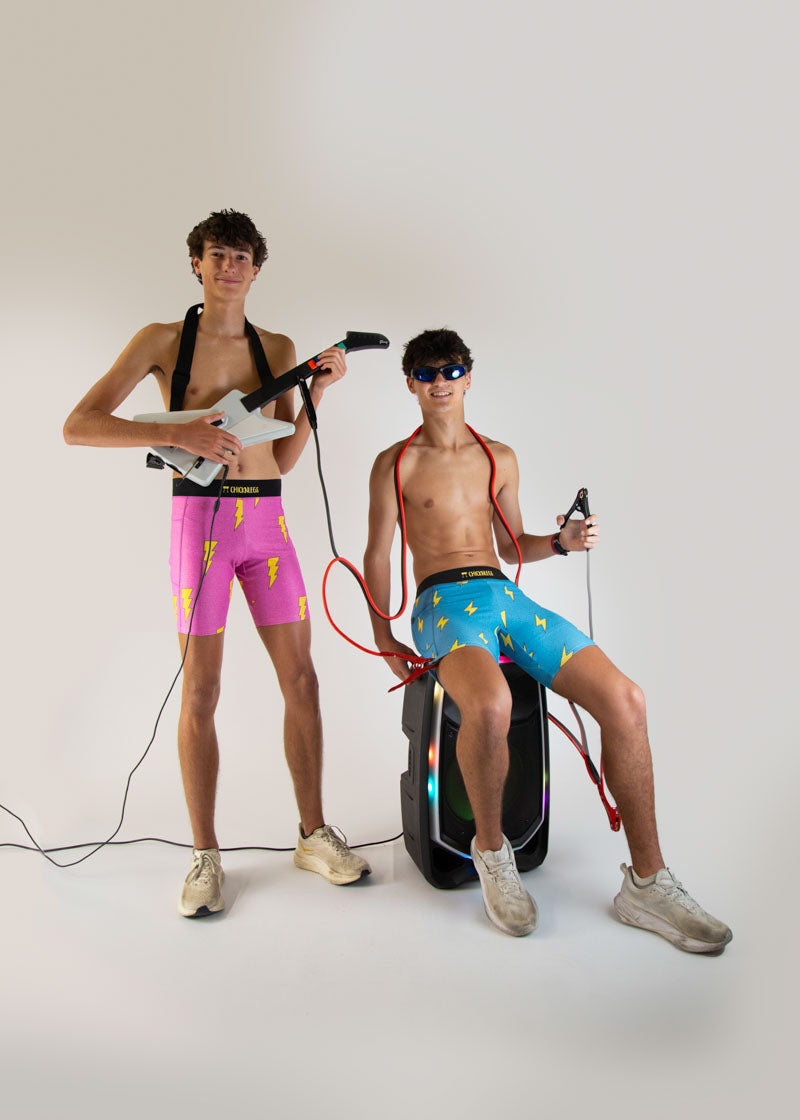 Two men modeling ChicknLegs athletic shorts with lightning bolt patterns in studio setting