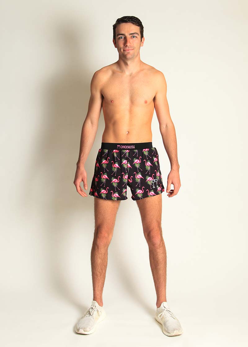 Man wearing black ChicknLegs shorts with pink flamingo pattern, studio photography