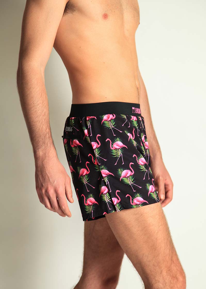 Man wearing black shorts with pink flamingo and tropical leaf pattern