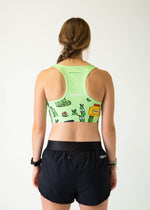Back view of woman wearing ChicknLegs green sports bra with pickle cartoon pattern