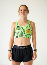 Woman wearing green sports bra with pickle pattern and black ChicknLegs shorts
