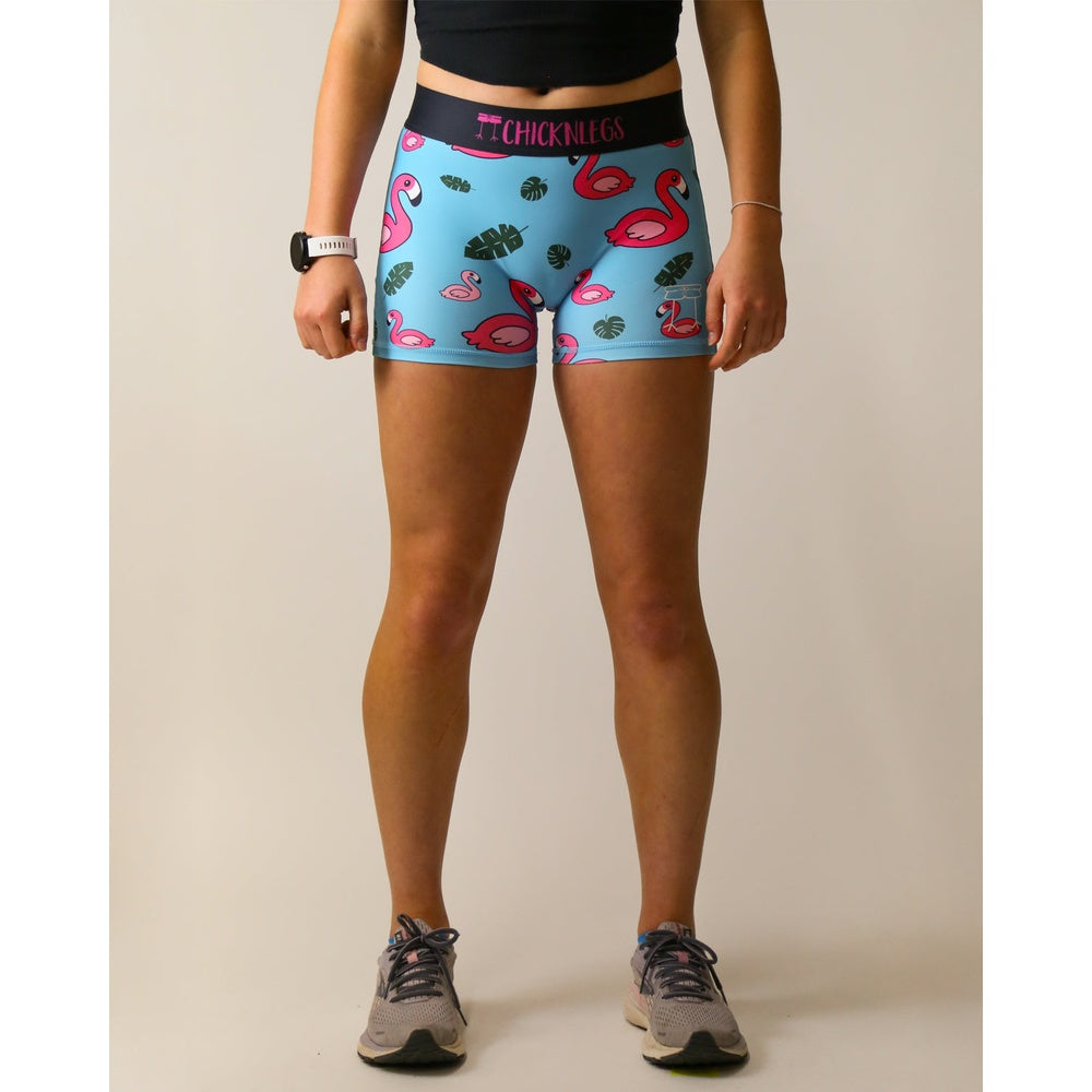 Woman wearing ChicknLegs blue compression shorts with pink flamingo and tropical leaf pattern