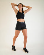 Female model wearing black ChicknLegs 3-inch compression shorts with matching crop top