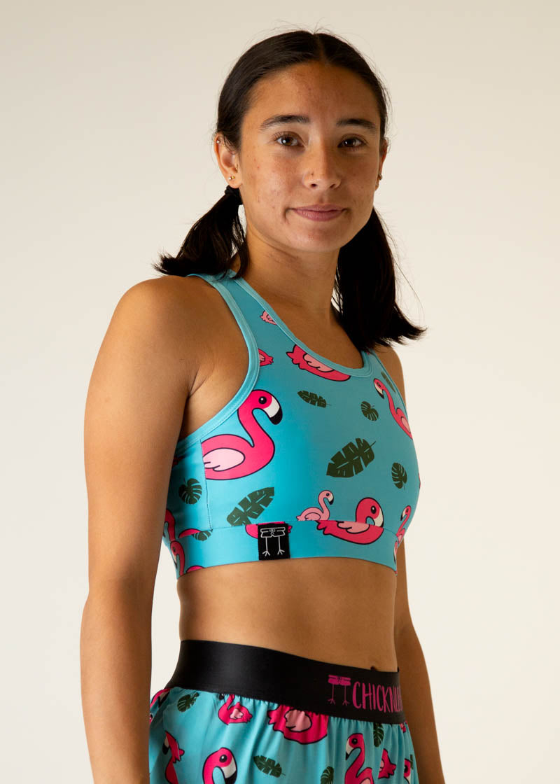 Woman wearing turquoise sports bra with pink flamingo pattern and matching shorts