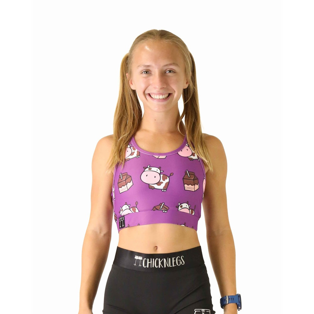 Purple sports bra with cartoon cow and chocolate milk pattern worn by smiling model