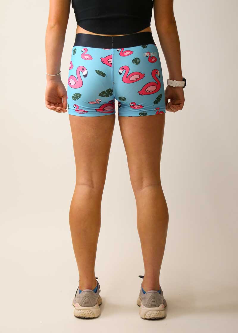 Woman wearing light blue compression shorts with pink flamingo and tropical leaf pattern