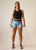 Woman wearing ChicknLegs blue compression shorts with flamingo pattern and black tank top