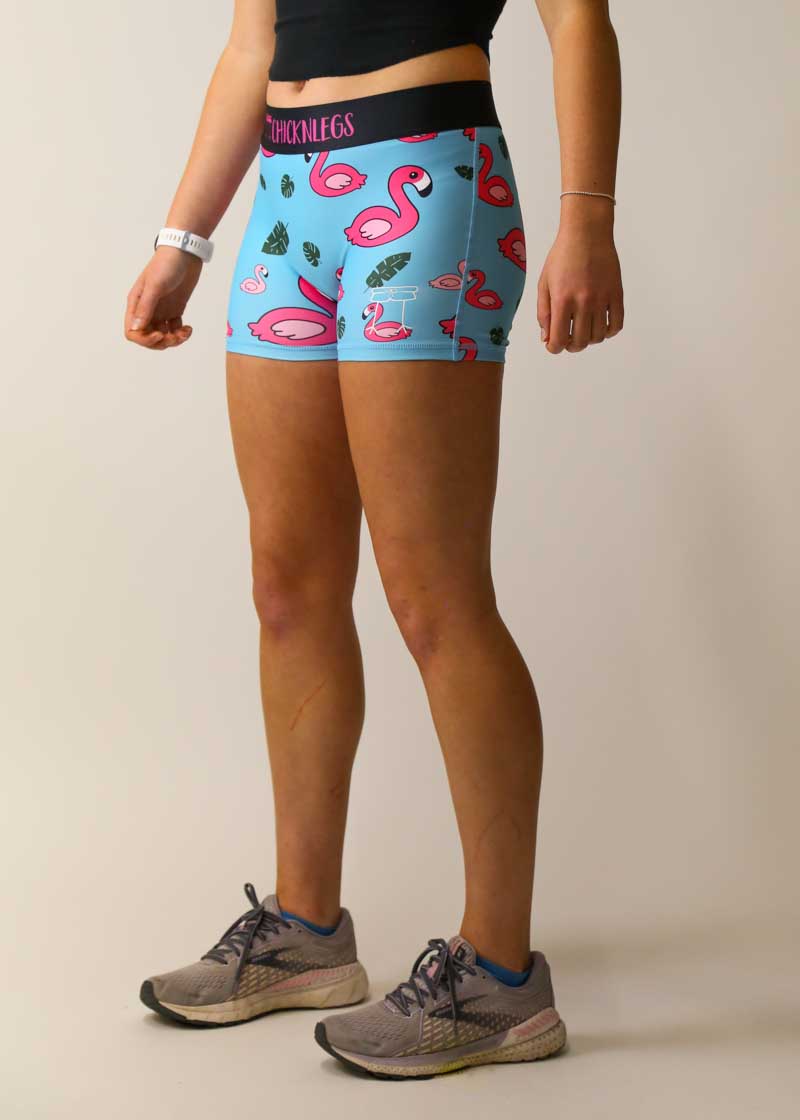 Woman wearing blue ChicknLegs compression shorts with pink flamingo and leaf pattern