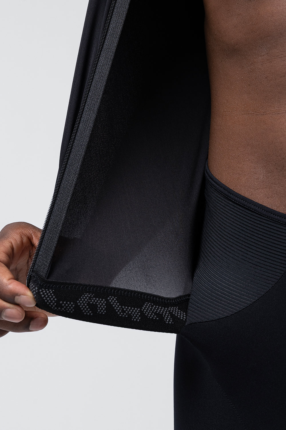 Close-up of black Gobik cycling jacket showing zipper detail and mesh ventilation panel