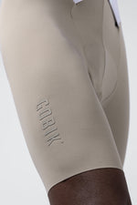 Close-up of Gobik branded bib shorts leg in beige sand color with embossed logo detail