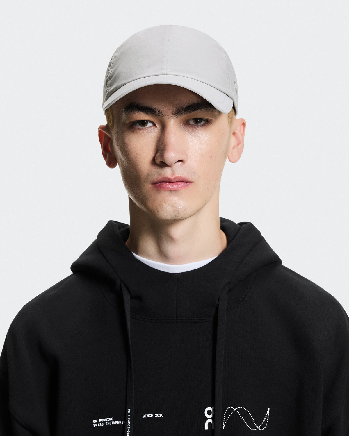 On Running unisex cap in alloy gray worn by male model in black hoodie