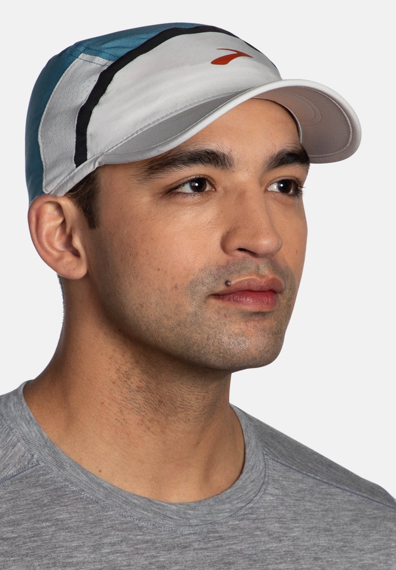Man wearing Brooks Base Hat in Storm Blue and Light Gray colorway with red logo