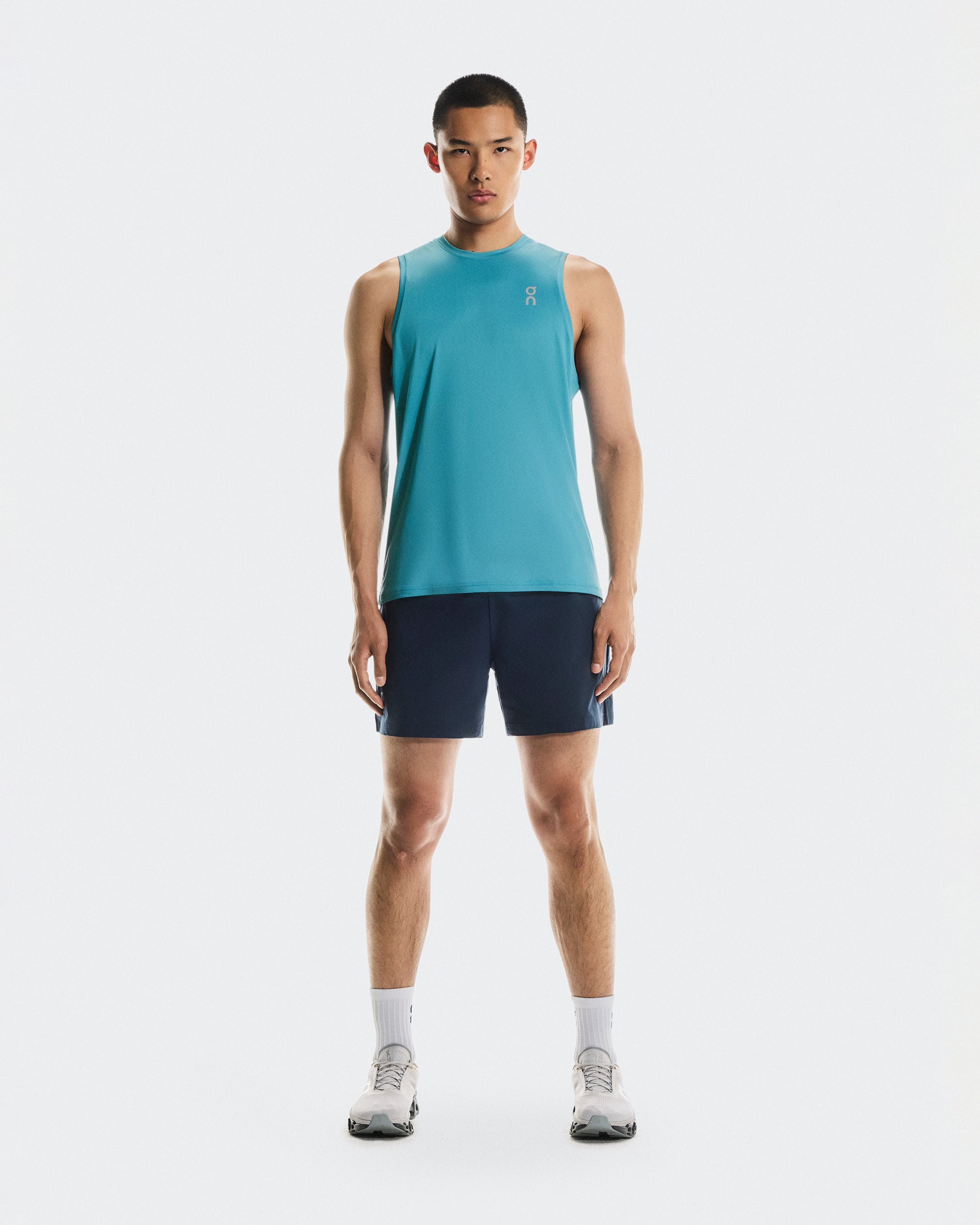Man wearing On Core Tank in turquoise blue with navy shorts and white sneakers
