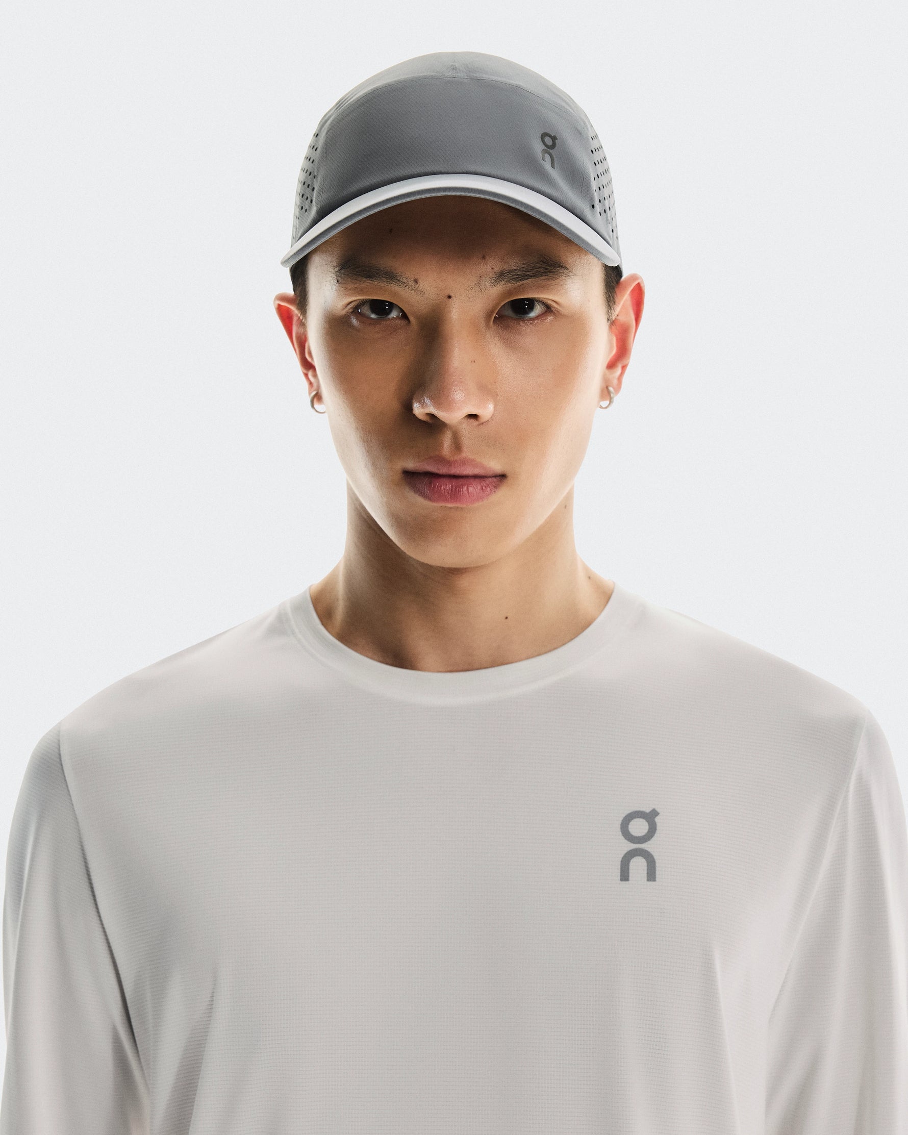Asian male model wearing On Lightweight Unisex Cap in gray/rock color with matching shirt