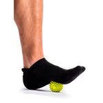 Person's foot in black sock rolling on green spiky TriggerPoint massage ball