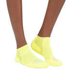 Person wearing bright yellow Experia no-show athletic socks on white background