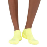 Person wearing bright yellow Experia no-show socks against white background
