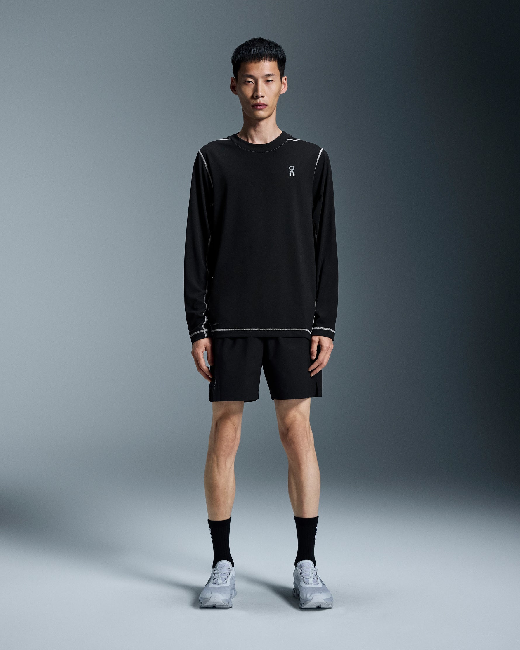 Man wearing black On 5 inch Core running shorts with matching long-sleeve shirt