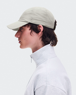 Model wearing On Performance Cap in Brume color with white quarter-zip sweatshirt, side profile view