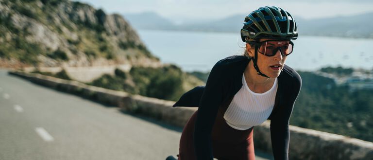 Cyclist wearing black Kask Valegro helmet while riding on scenic coastal road