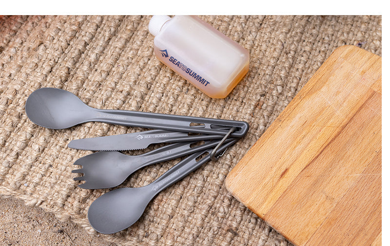 Sea to Summit grey ultralight cutlery set with spork, knife, and carrying case on textured surface