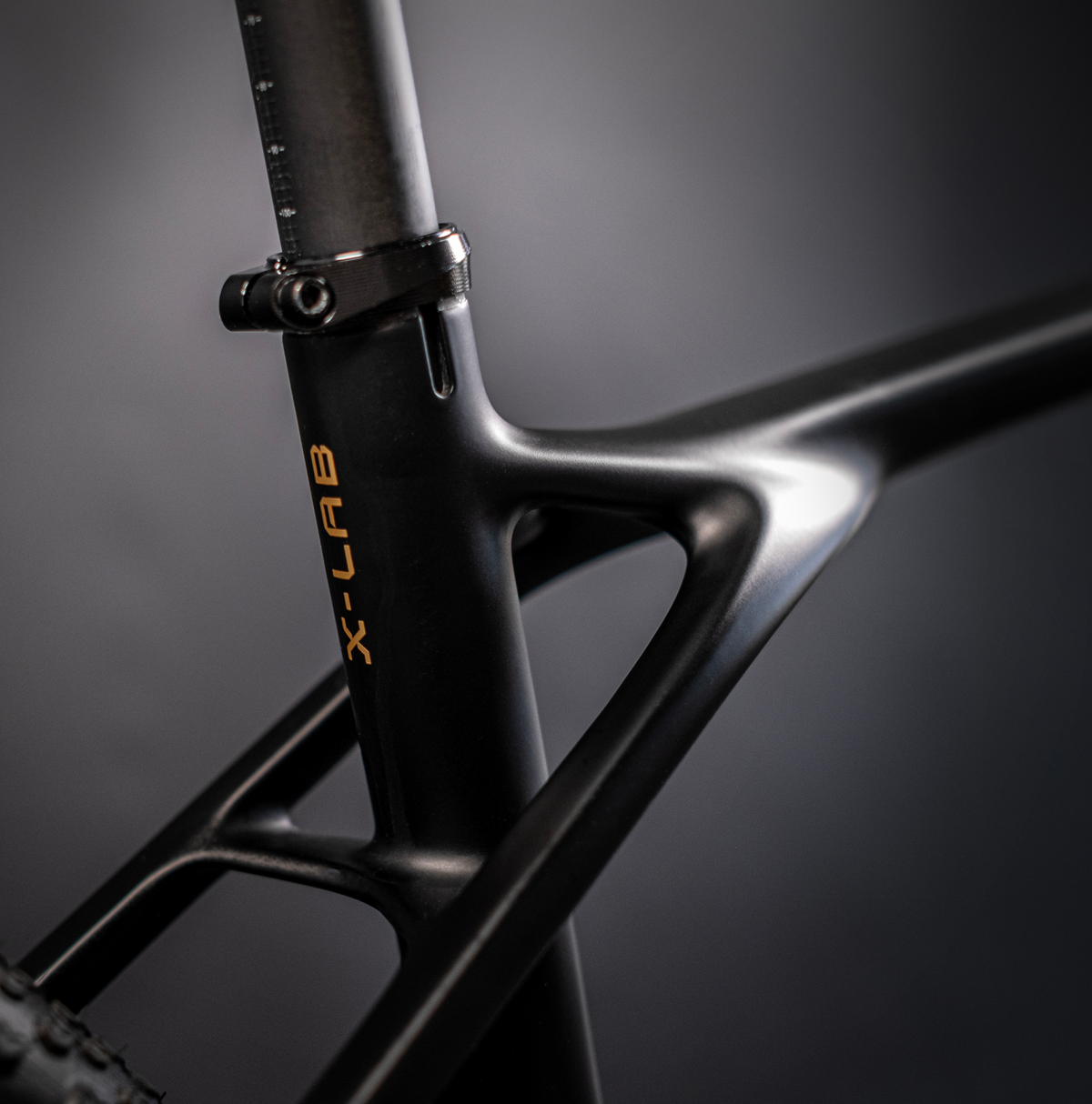 Close-up detail of X-LAB GT8 seat tube junction showing carbon construction and gold brand lettering