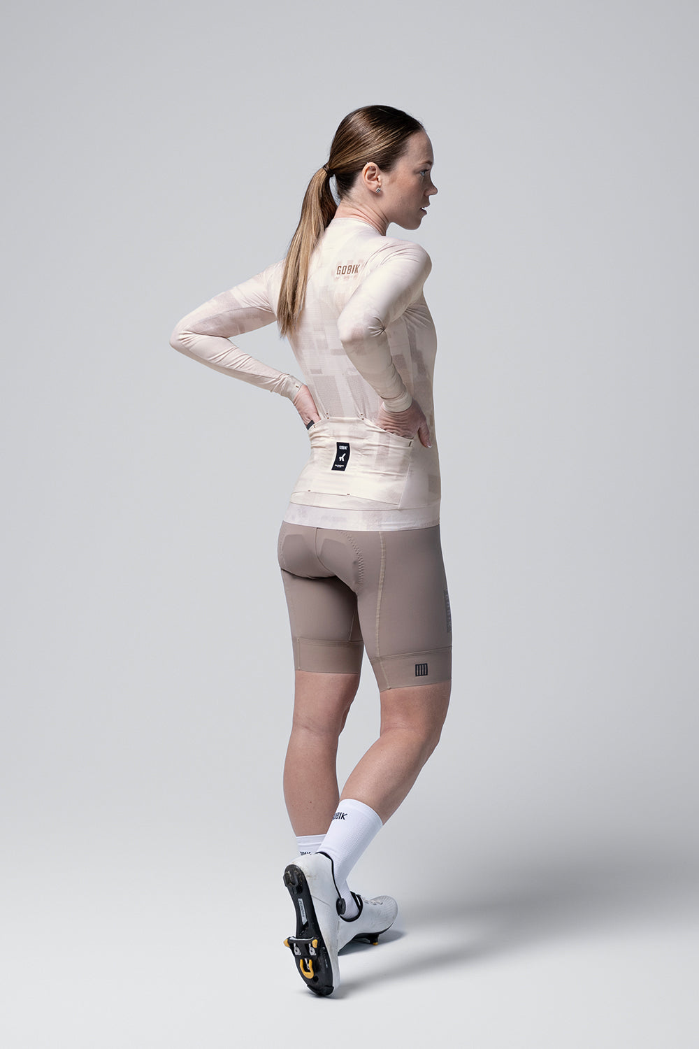 Female cyclist wearing Gobik Vanquish long sleeve jersey in whisper pink with cycling shorts