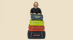 Man showcasing stack of Patagonia Black Hole duffel bags in multiple colors and sizes