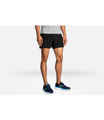 Man wearing Brooks Sherpa 5-inch 2-in-1 running shorts in black with blue Brooks sneakers